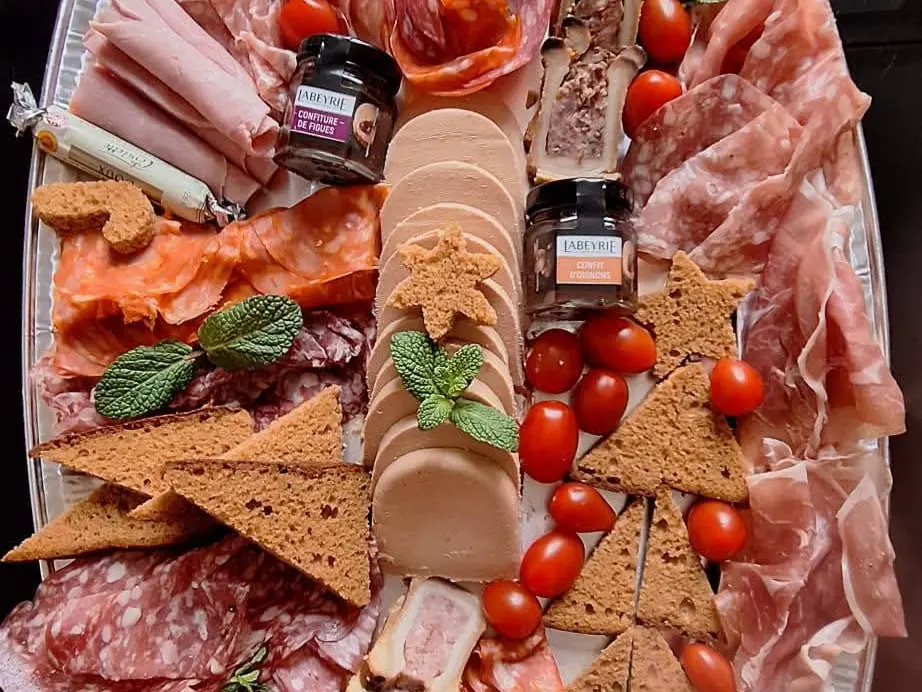 Grand plateau de charcuterie à partager : jambons, saucisson, pâté, pain d'épices et tomates cerises